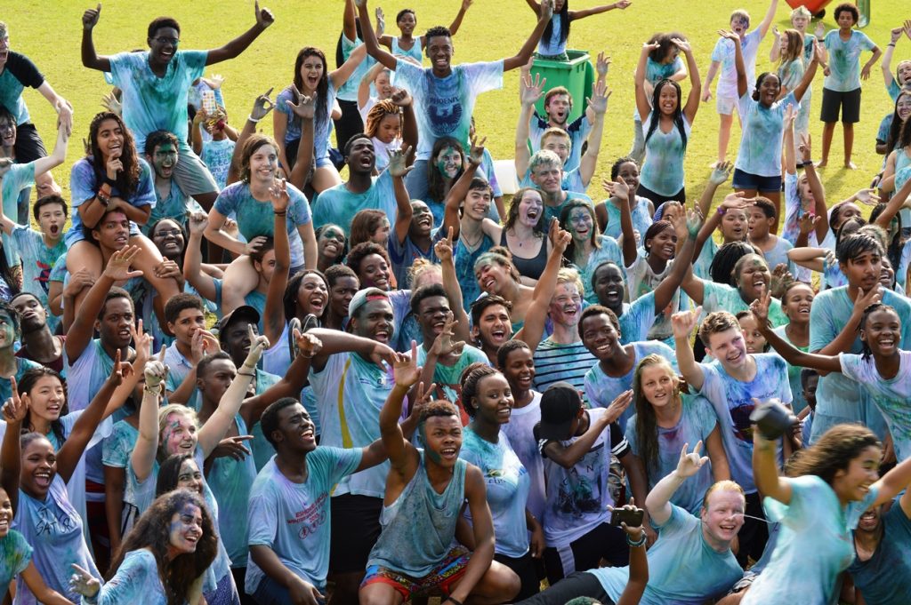Large group of student wearing UWC green t-shirts with arms in the air cheering