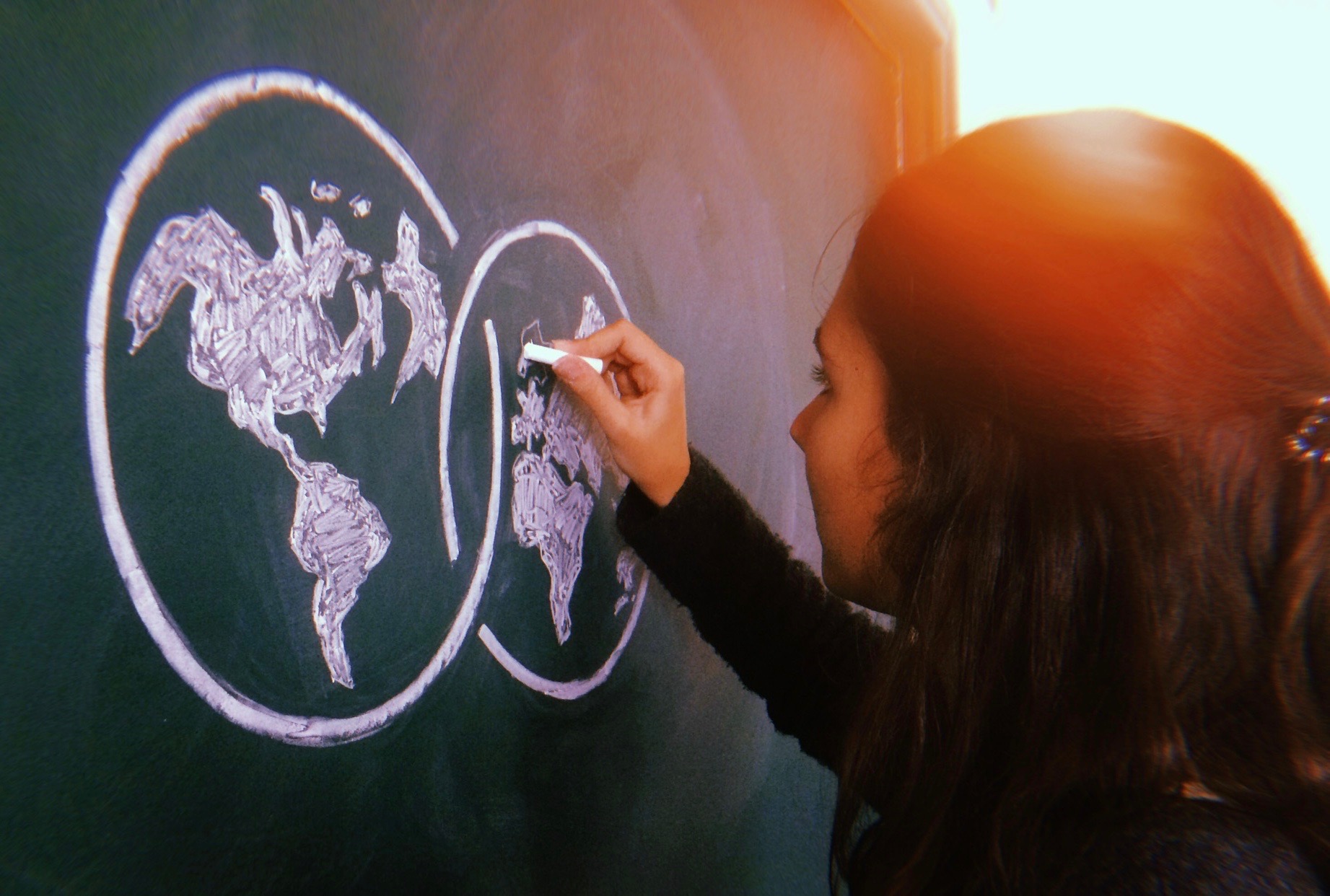 Student drawing a global on a chalk board