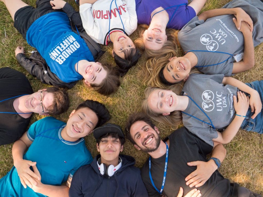 Students lying down in a circle looking up at the camera